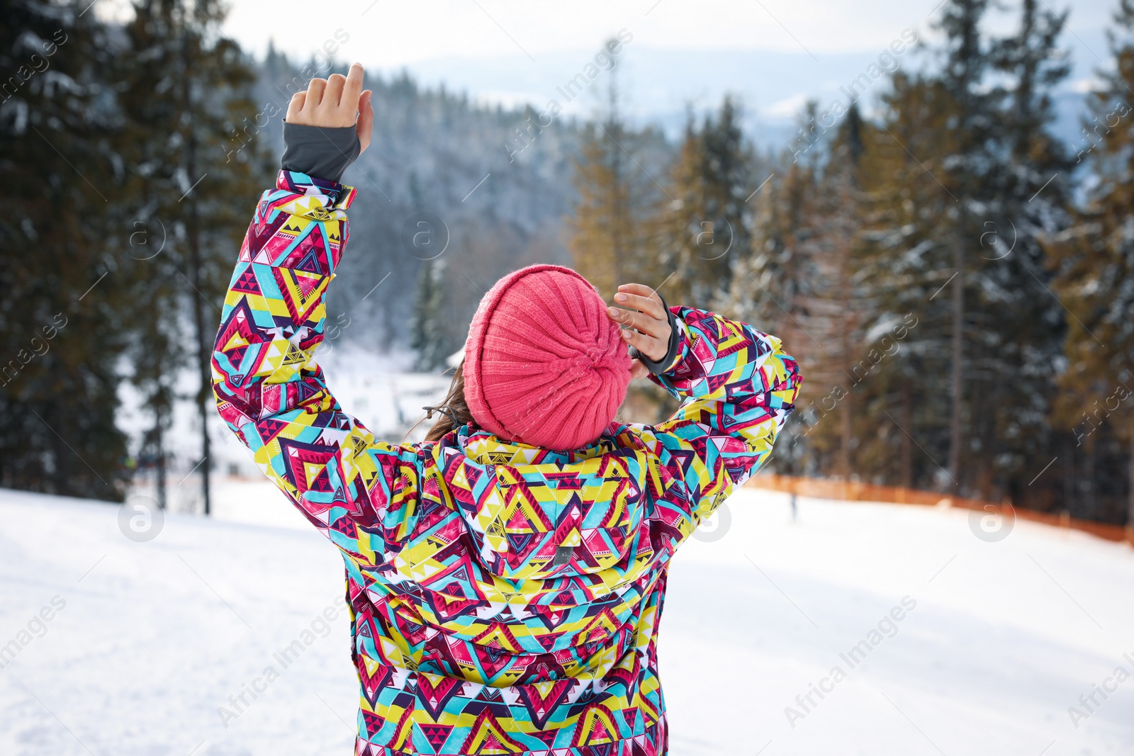 Photo of Young woman at mountain resort, back view. Winter vacation