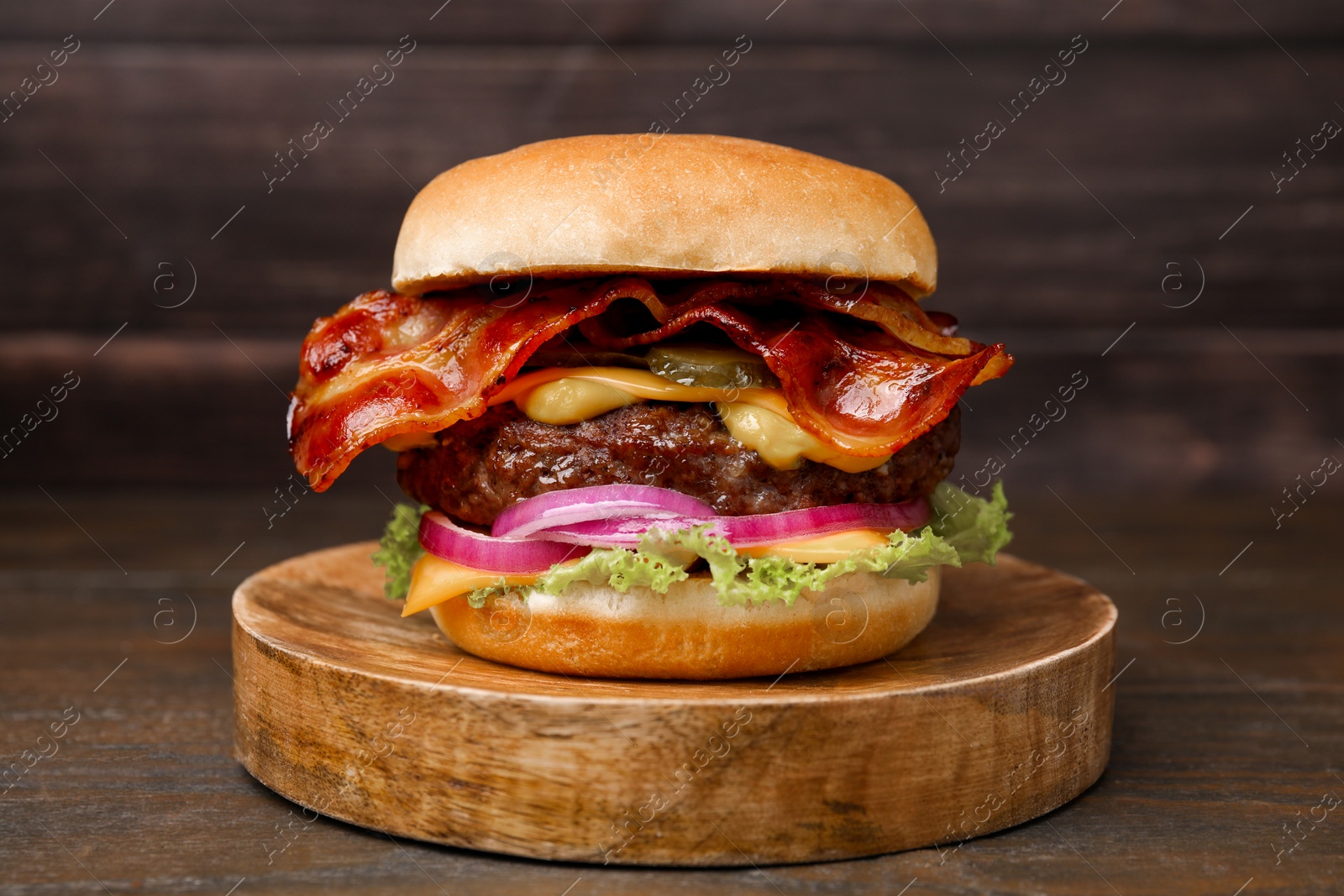 Photo of Tasty burger with bacon, vegetables and patty on wooden table