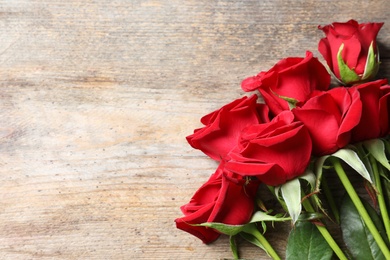 Photo of Beautiful red rose flowers on wooden background, top view