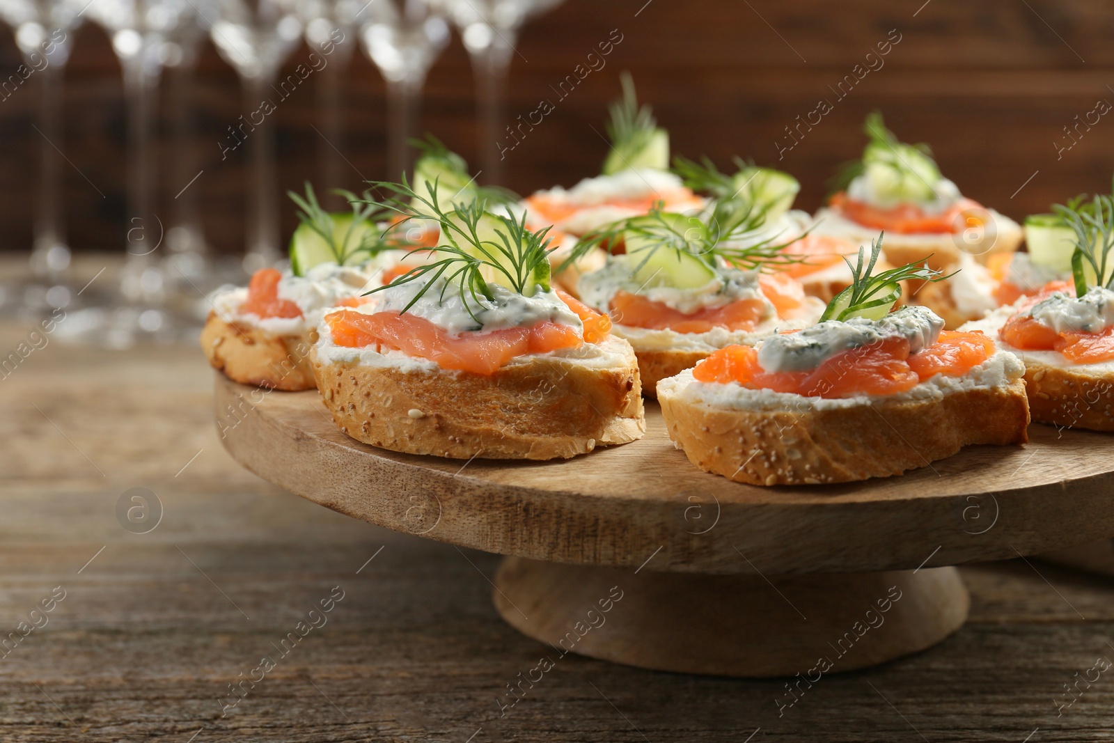 Photo of Tasty canapes with salmon, cucumber, cream cheese and dill on wooden table, closeup