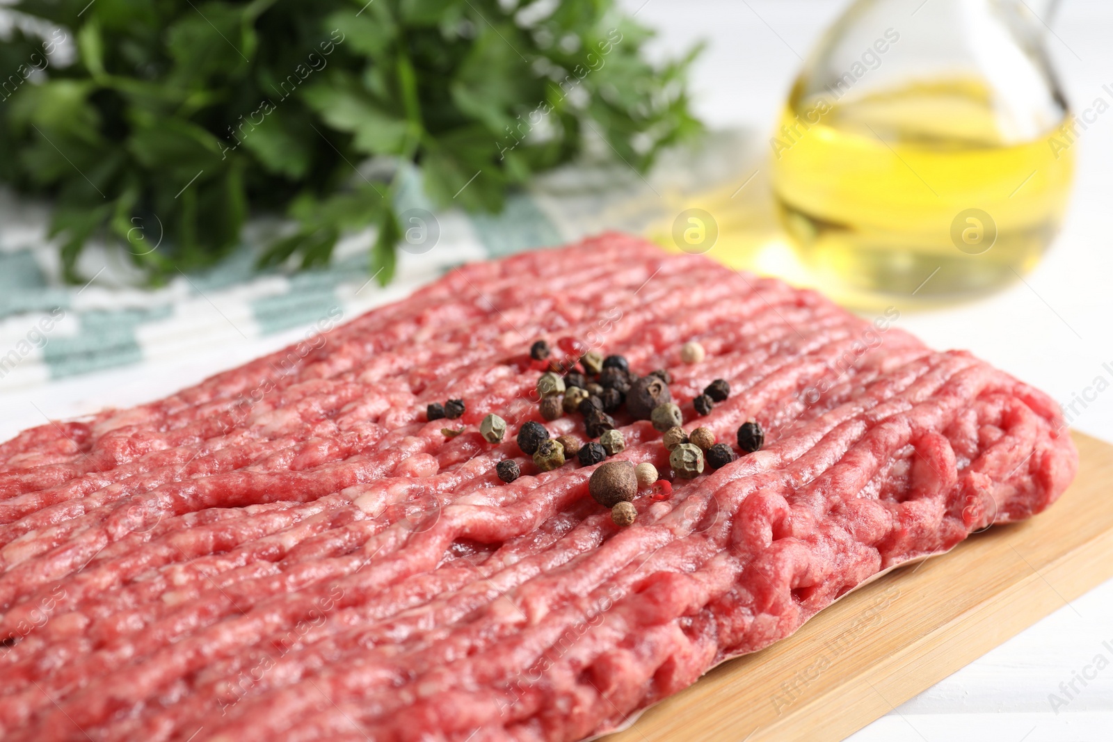 Photo of Raw ground meat and peppercorns on table, closeup