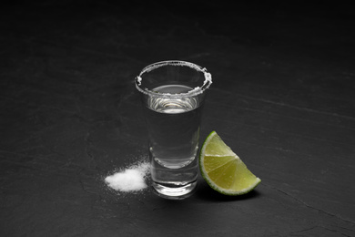 Mexican Tequila shot with salt and lime slice on black table