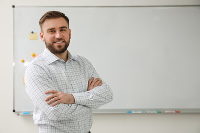 Photo of Portrait of young teacher near whiteboard in classroom. Space for text