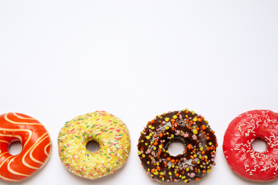 Delicious glazed donuts on white background, flat lay. Space for text