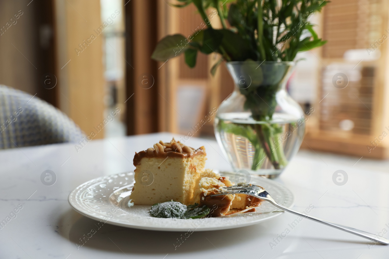 Photo of Tasty dessert and vase with flowers on white table indoors