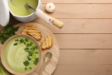 Photo of Delicious leek soup served on beige wooden table, flat lay. Space for text