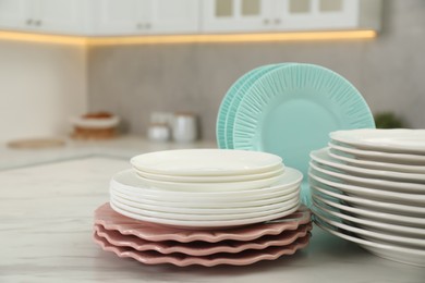 Photo of Clean plates on white marble table in kitchen