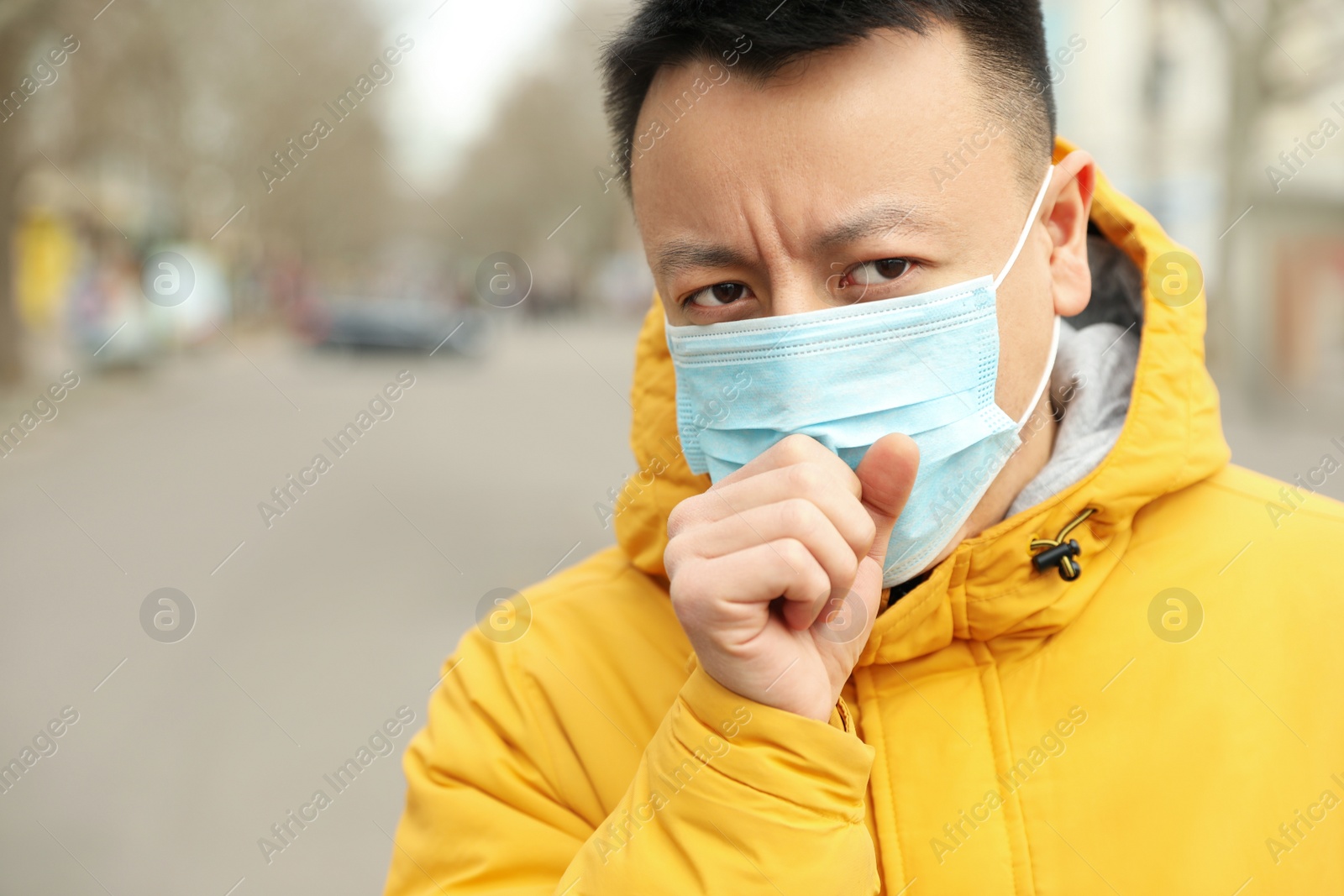Photo of Asian man wearing medical mask on city street, space for text. Virus outbreak