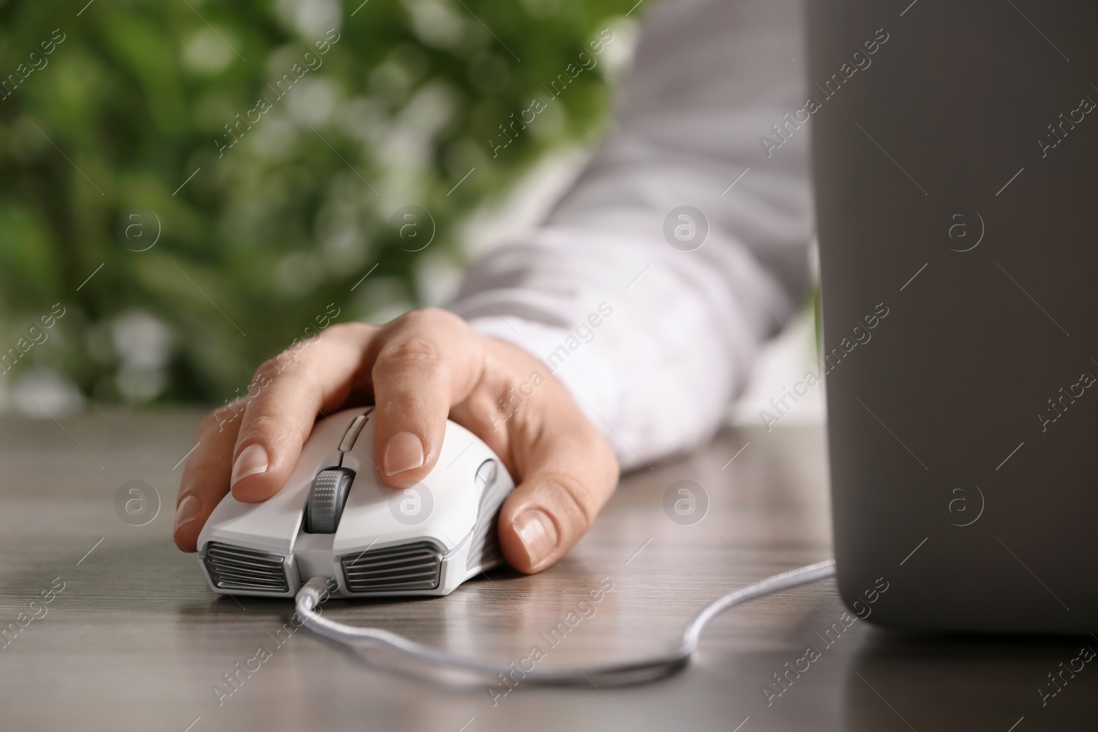 Photo of Woman using computer mouse with laptop at table, closeup