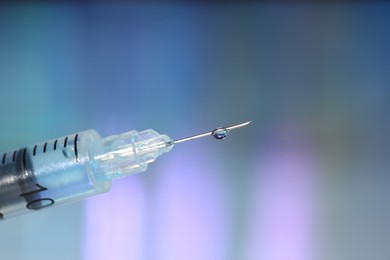 Syringe with medicine against blurred background, closeup. Space for text