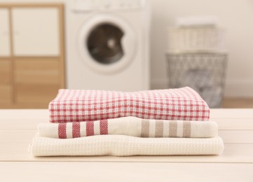 Photo of Stack of clean kitchen towels on white wooden table in laundry room