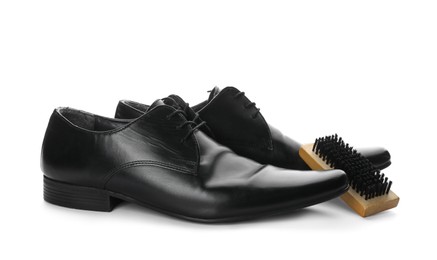 Photo of Black men's shoes and brush on white background. Footwear care