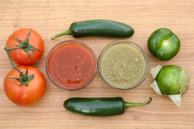 Photo of Tasty salsa sauces, jalapeno peppers and different tomatoes on wooden table, flat lay