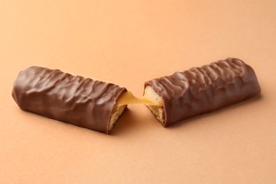 Photo of Pieces of chocolate bar with caramel on beige background