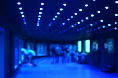 Blurred view of room with ceiling lights and people, bokeh effect