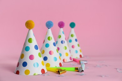 Photo of Colorful party hats with fluffy balls and blowers on pink background