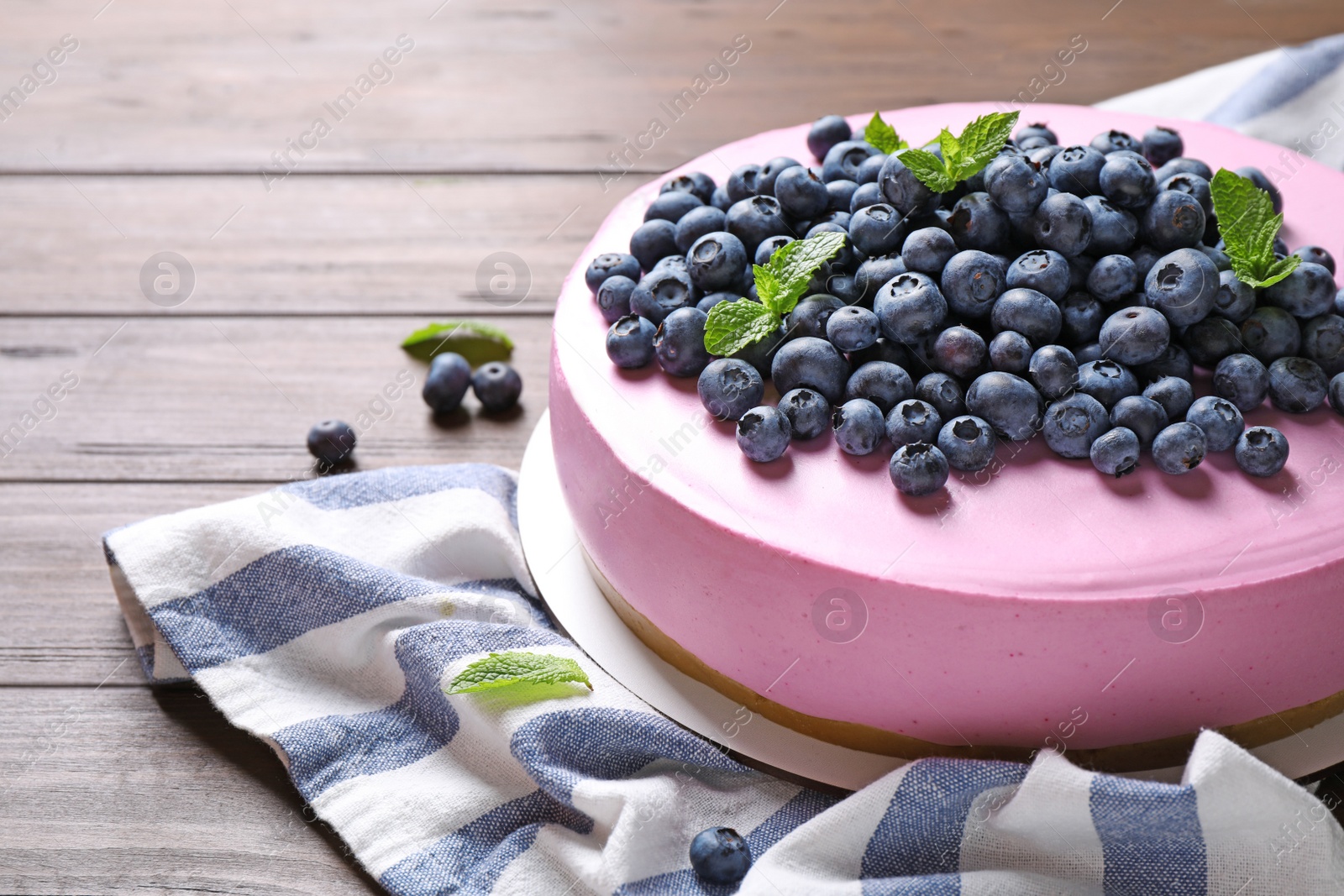 Photo of Tasty blueberry cake and napkin on wooden table. Space for text