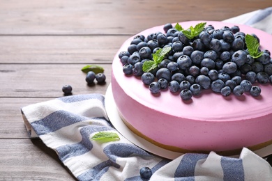 Photo of Tasty blueberry cake and napkin on wooden table. Space for text