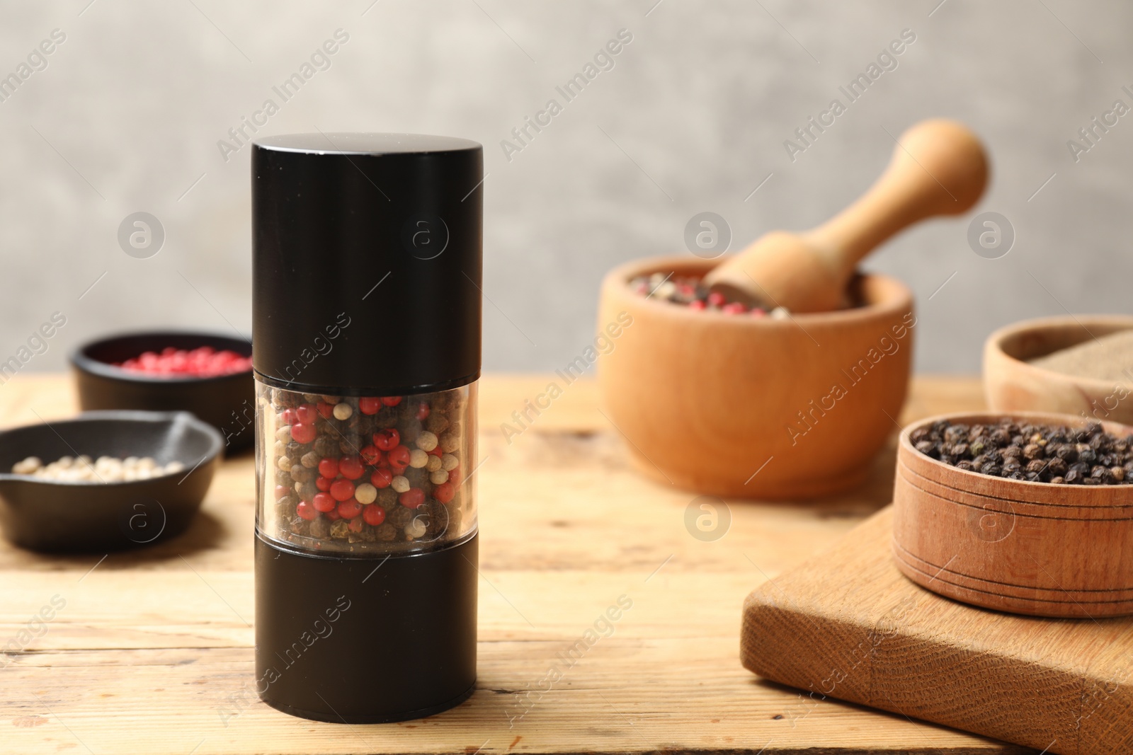 Photo of Different peppercorns on wooden table, closeup. Space for text