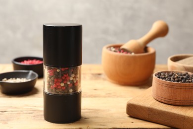 Photo of Different peppercorns on wooden table, closeup. Space for text