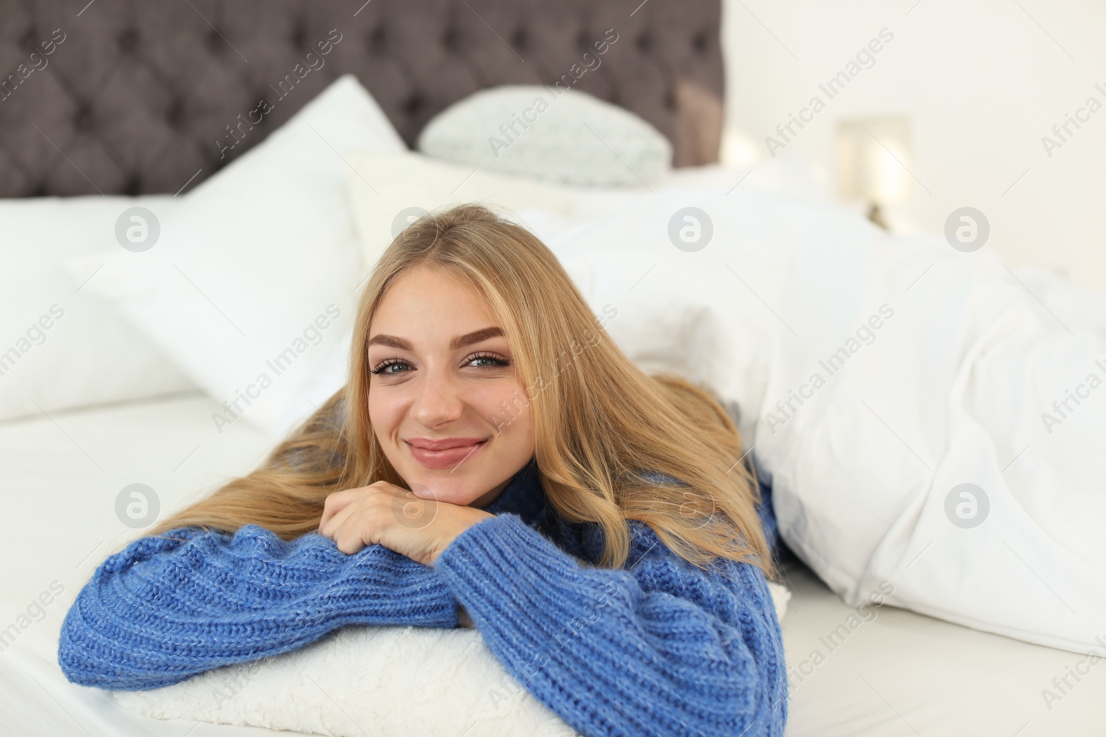 Photo of Beautiful young woman lying on pillow in bed at home. Winter atmosphere