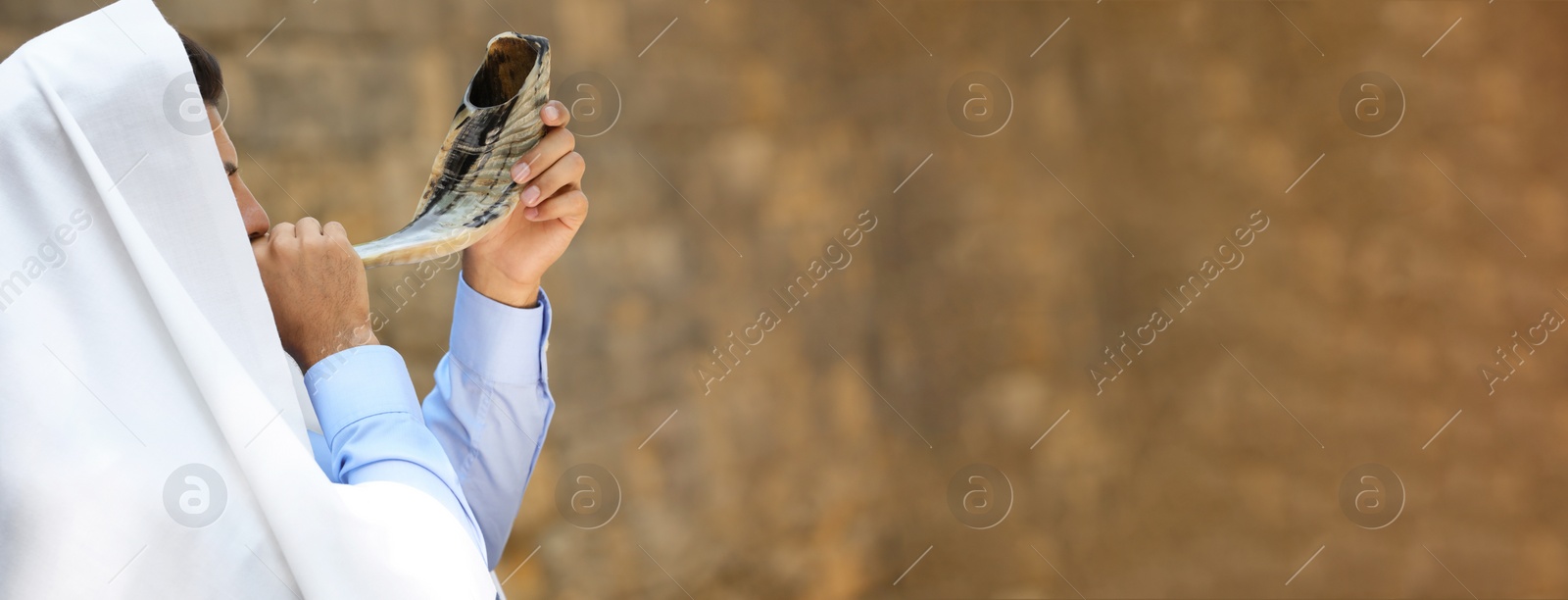 Image of Jewish man in tallit blowing shofar outdoors, banner design. Rosh Hashanah celebration