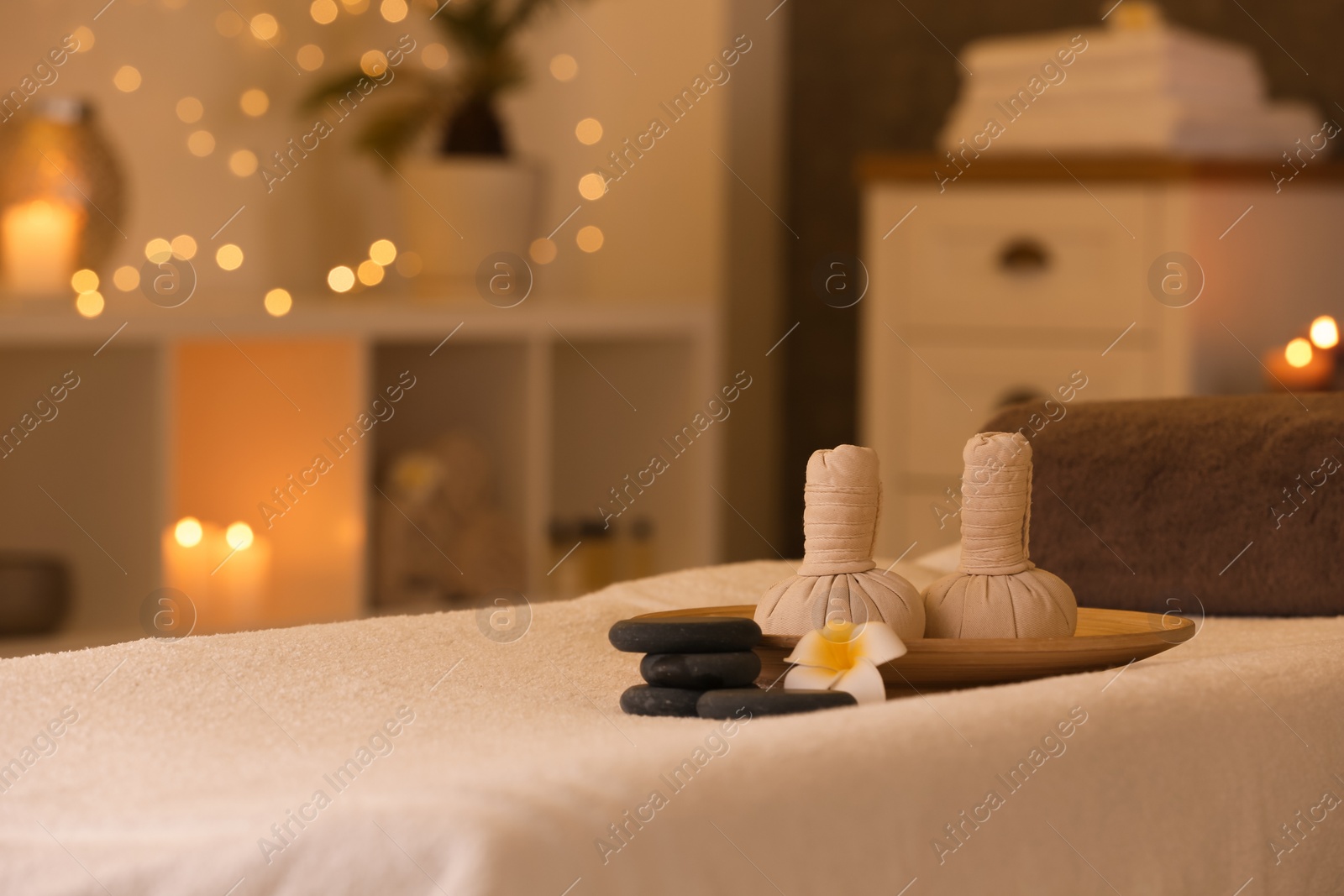 Photo of Herbal compresses and stones on massage table in spa salon. Space for text