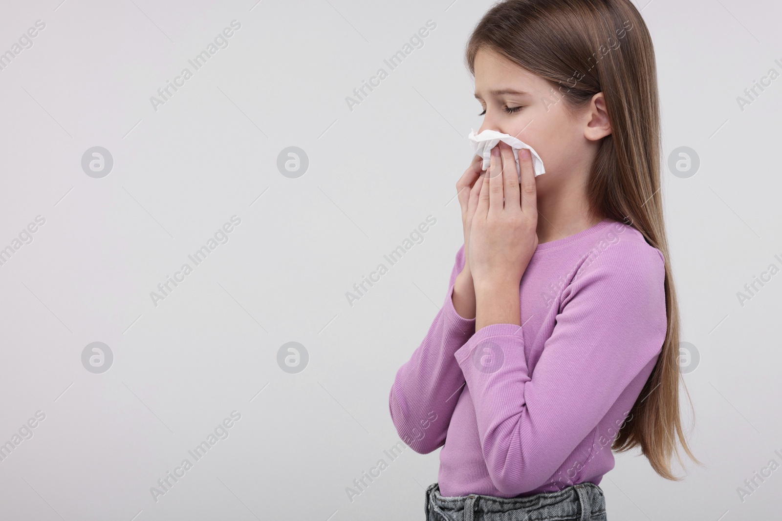 Photo of Sick girl with tissue coughing on light background, space for text