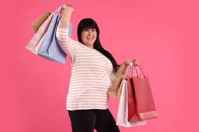 Photo of Beautiful overweight mature woman with shopping bags on pink background