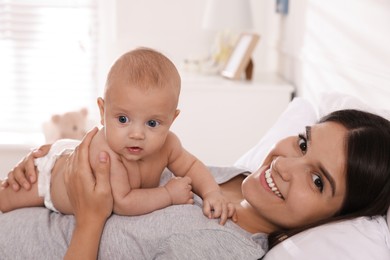 Photo of Happy young mother with her cute baby on bed at home