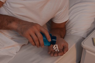 Man suffering from insomnia taking pills in bed at night, closeup