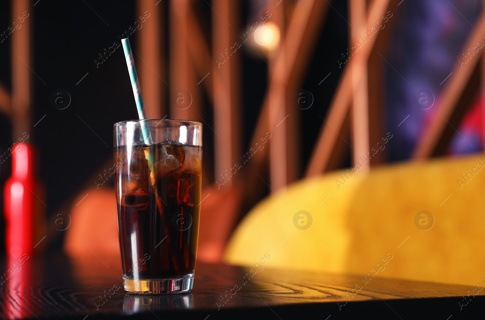 Photo of Glass of refreshing cola with ice on table indoors. Space for text