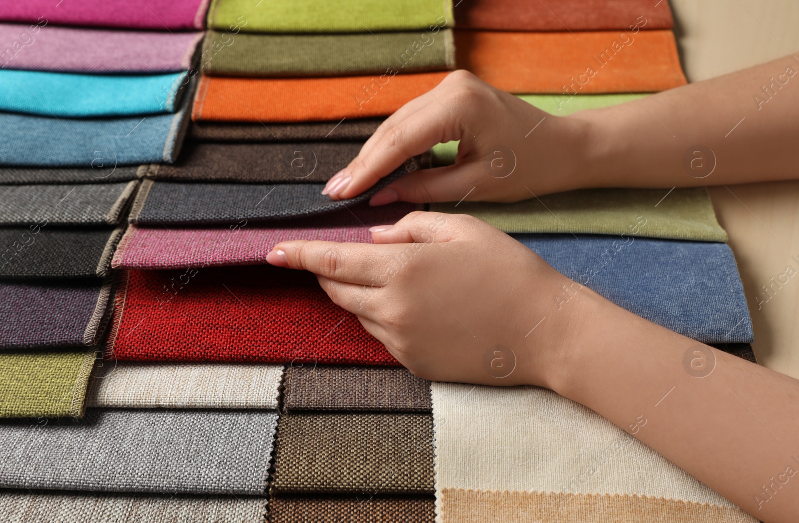 Photo of Woman choosing fabric among multicolored samples, closeup