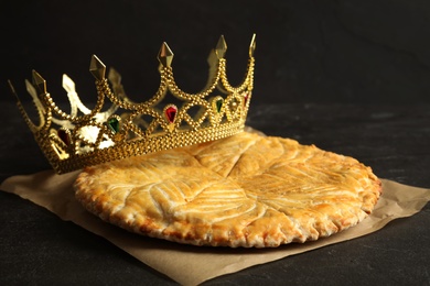 Traditional galette des Rois with decorative crown on black table
