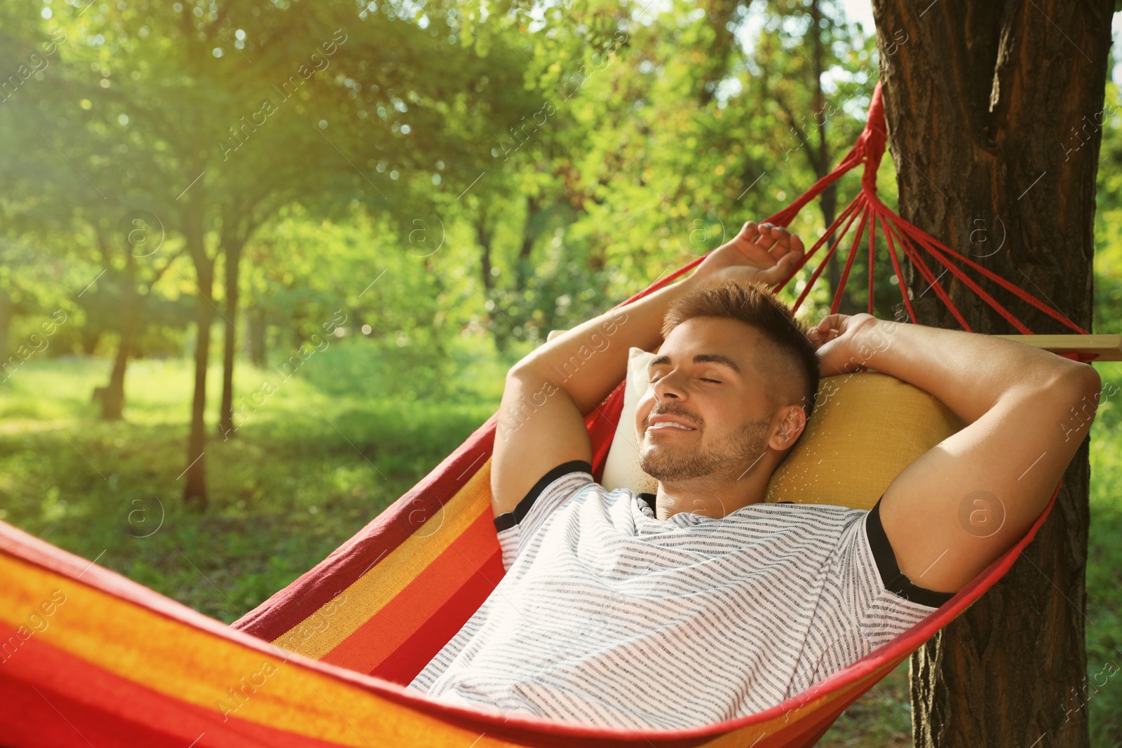 Photo of Young man resting in comfortable hammock at green garden