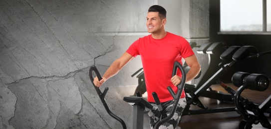 Image of Man using modern elliptical machine in gym, space for text. Banner design