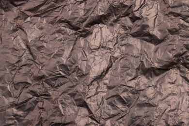 Photo of Crumpled black plastic bag as background, top view