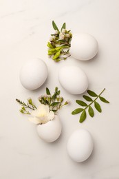 Photo of Easter eggs and beautiful flowers on white marble table, flat lay