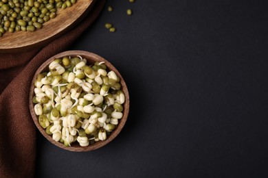 Photo of Wooden bowl with sprouted green mung beans on black background, flat lay. Space for text
