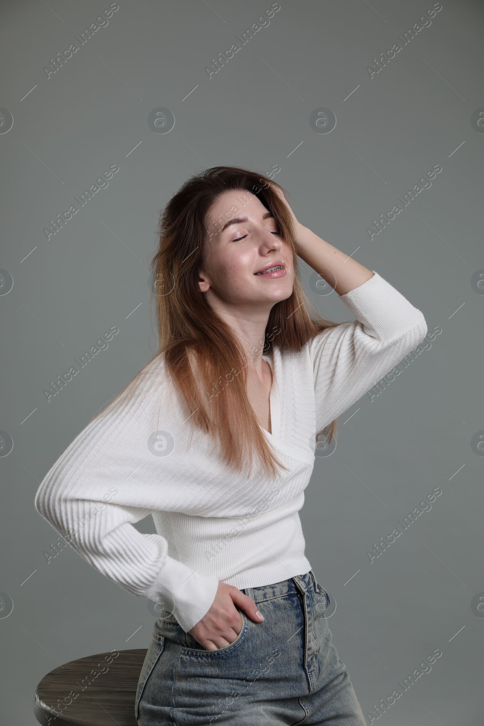 Photo of Beautiful young woman sitting on stool against grey background