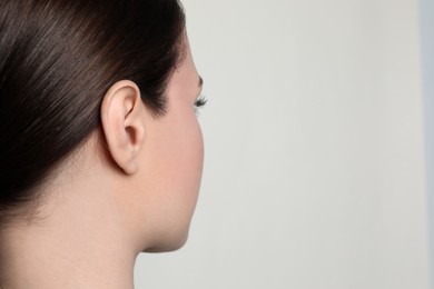 Woman on light background, closeup of ear. Space for text