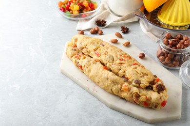 Photo of Unbaked Stollen with candied fruits and raisins on light marble table. Space for text