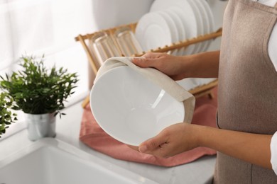 Photo of Woman wiping bowl with towel in kitchen, closeup