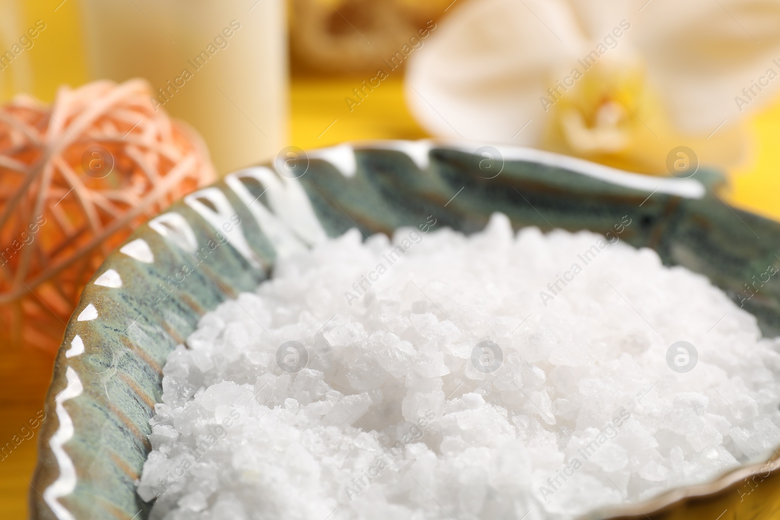 Photo of Natural sea salt in bowl on table, closeup