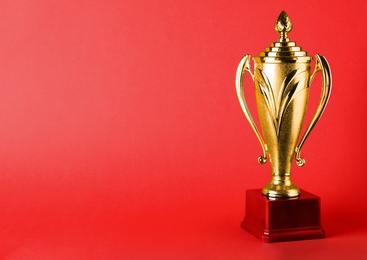 Photo of Golden trophy cup on red background. Space for text