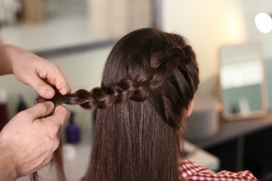 Professional hairdresser working with client in beauty salon, closeup