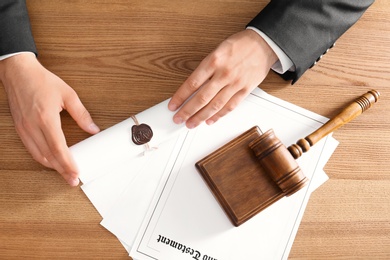 Male notary working at wooden table, top view