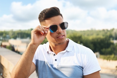 Photo of Handsome man wearing stylish sunglasses on city street