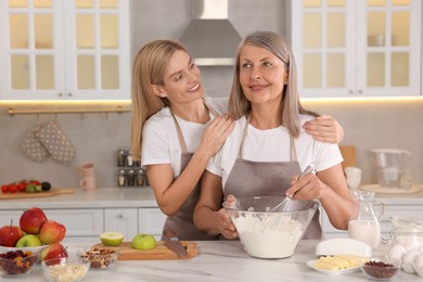Photo of Happy mature mother and her daughter cooking together at kitchen
