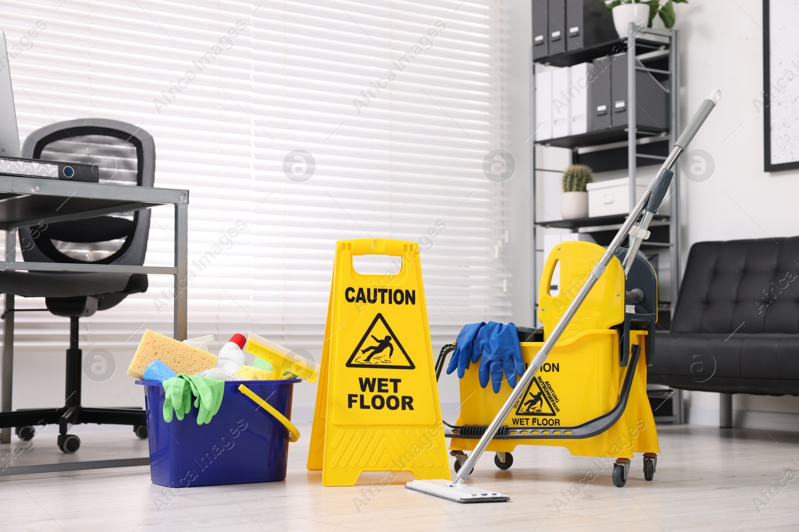 Photo of Cleaning service. Mop, wet floor sign and bucket with supplies in office